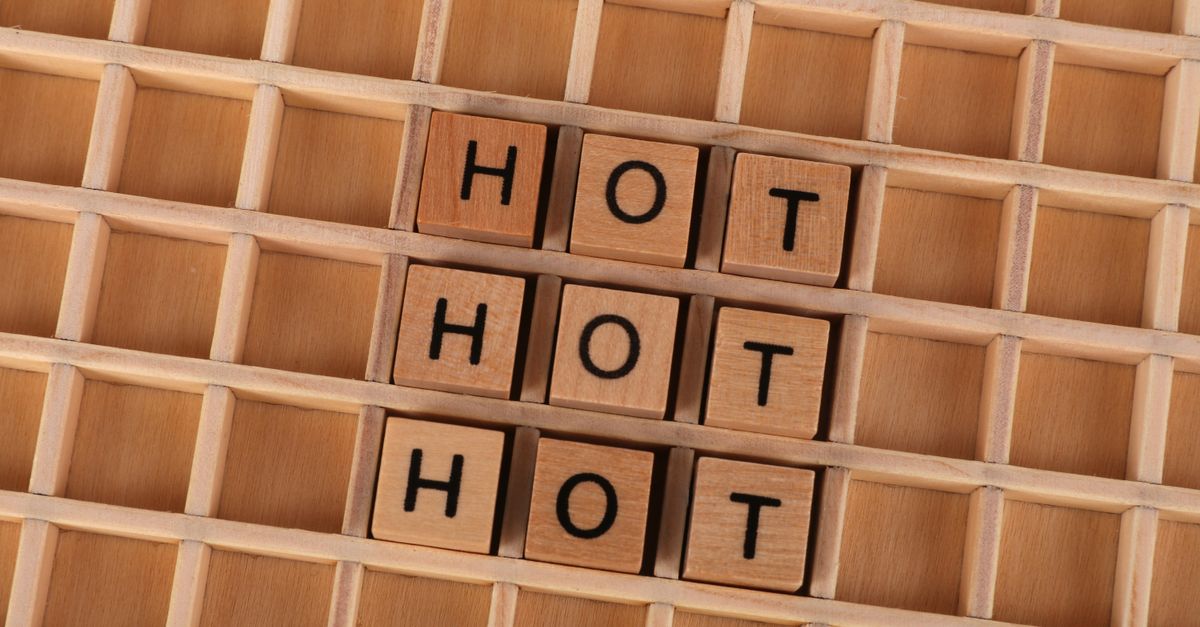 Wooden letter tiles forming the word 'HOT' on a wooden grid background.